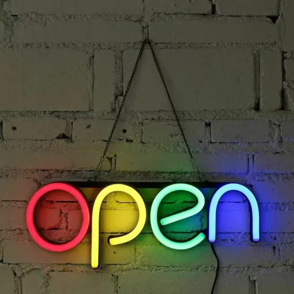 "Open" rainbow-colored neon sign hanging on a rustic brick wall.