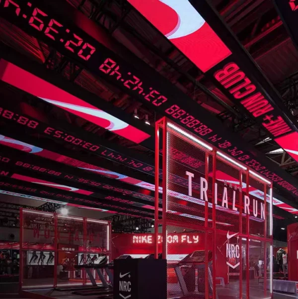 An industrial-themed interior with red and black lighting showcases a custom Full Color LED Digital Display Sign, WiFi & USB Programmable, featuring scrolling text, images, and video. A Trial Run area with mesh walls and Nike branding enhances the sports-inspired ambiance.