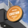 A round, orange sign on the building states YOU SIGN CUSTOM you design here, paired with Solar Signs Light Boxes featuring energy-efficient, double-sided illumination. Solar panels atop the roof, under scattered clouds against a blue sky, complete this eco-friendly display of weatherproof outdoor signage.